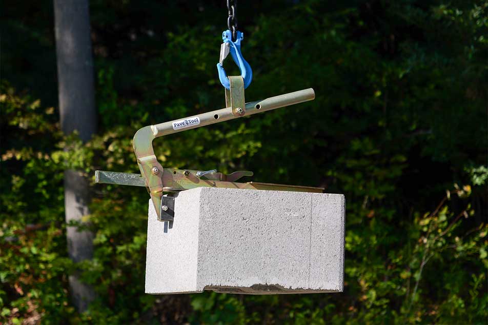 Cement block being lifted by a crane with a blurred green background