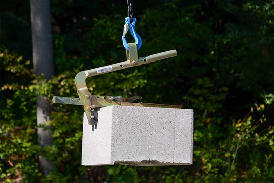 Cement block being lifted by a crane with a blurred green background
